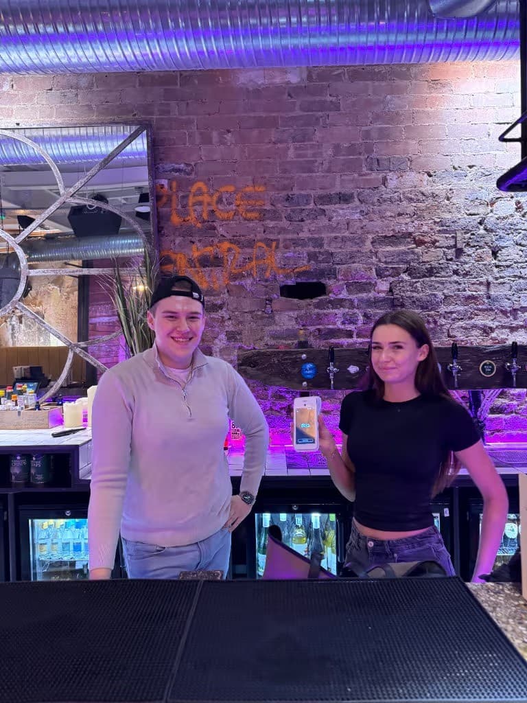 Two members of bar staff taking a payment on their Dojo card machine, set up by CapExpand