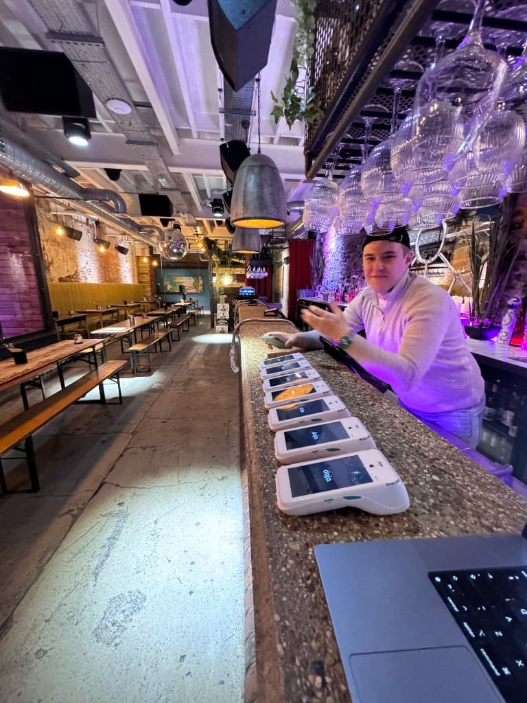 A row of Dojo terminals lined up on the bar at The Green Room, Leeds, during setup